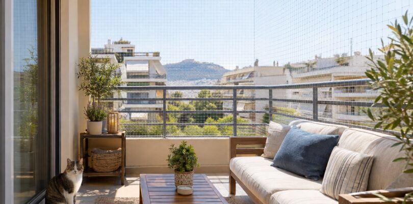 Γάτα σε ασφαλές μπαλκόνι ενοικιαζόμενου σπιτιού με διακριτικό προστατευτικό δίχτυ